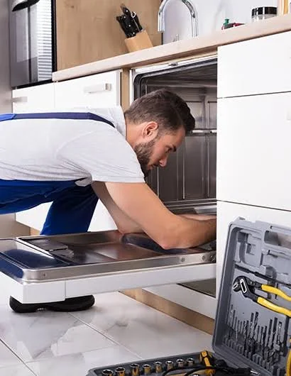 Technician servicing a built-in dishwasher in a residential kitchen